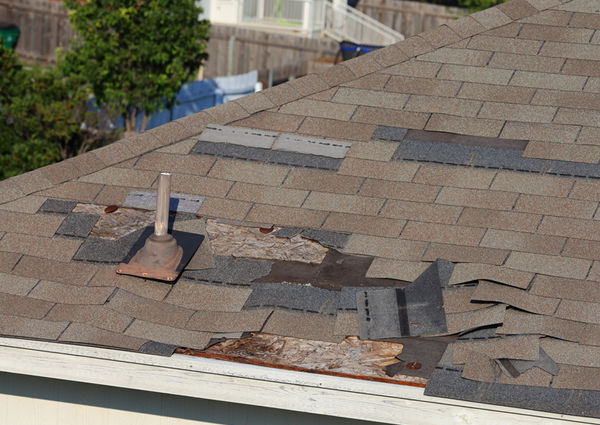 Roof of home with peeling asphalt shingles.