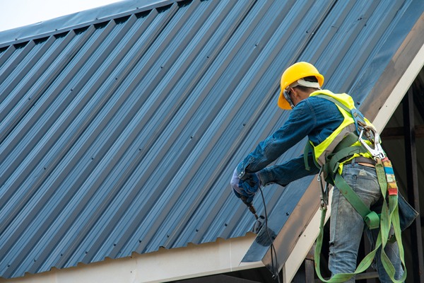 A contractor working safely on a metal roof while wearing PPE